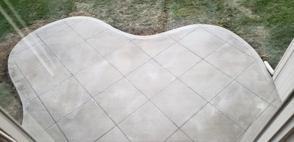 curved concrete patio with grid pattern beside a grassy yard