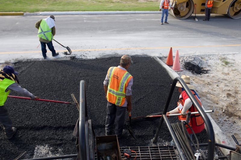 Workers installing asphalt driveway surface at a residential property