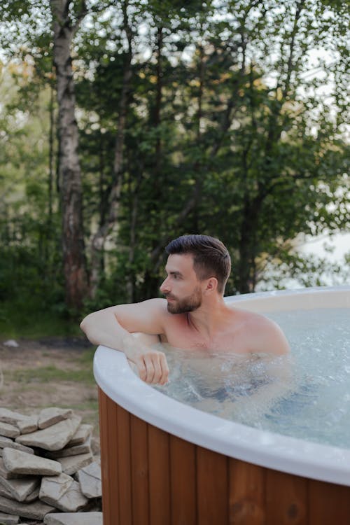 Person relaxing in an outdoor jacuzzi spa on a residential patio in the evening