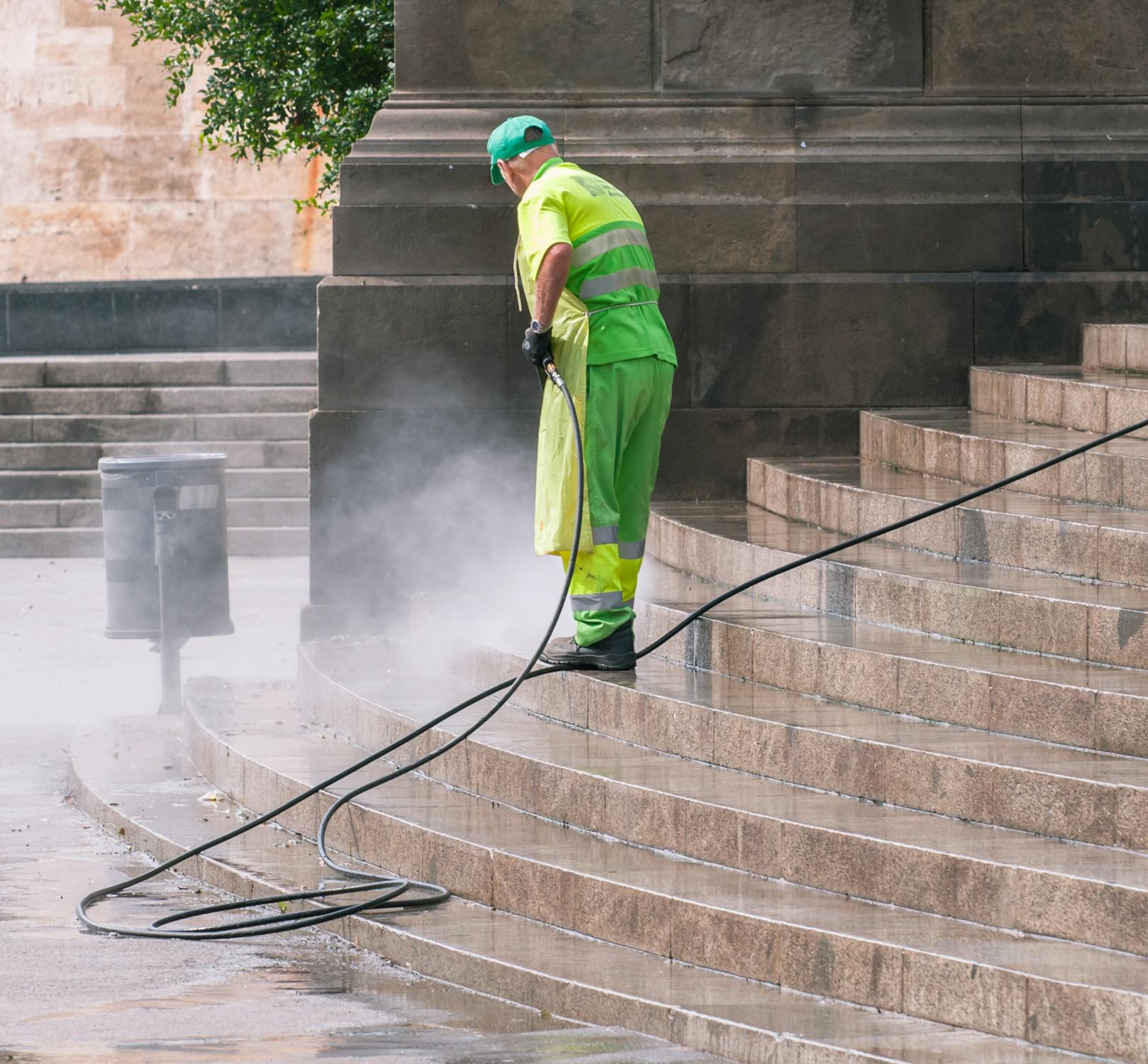 Worker pressure washing outdoor concrete steps during spring cleaning season